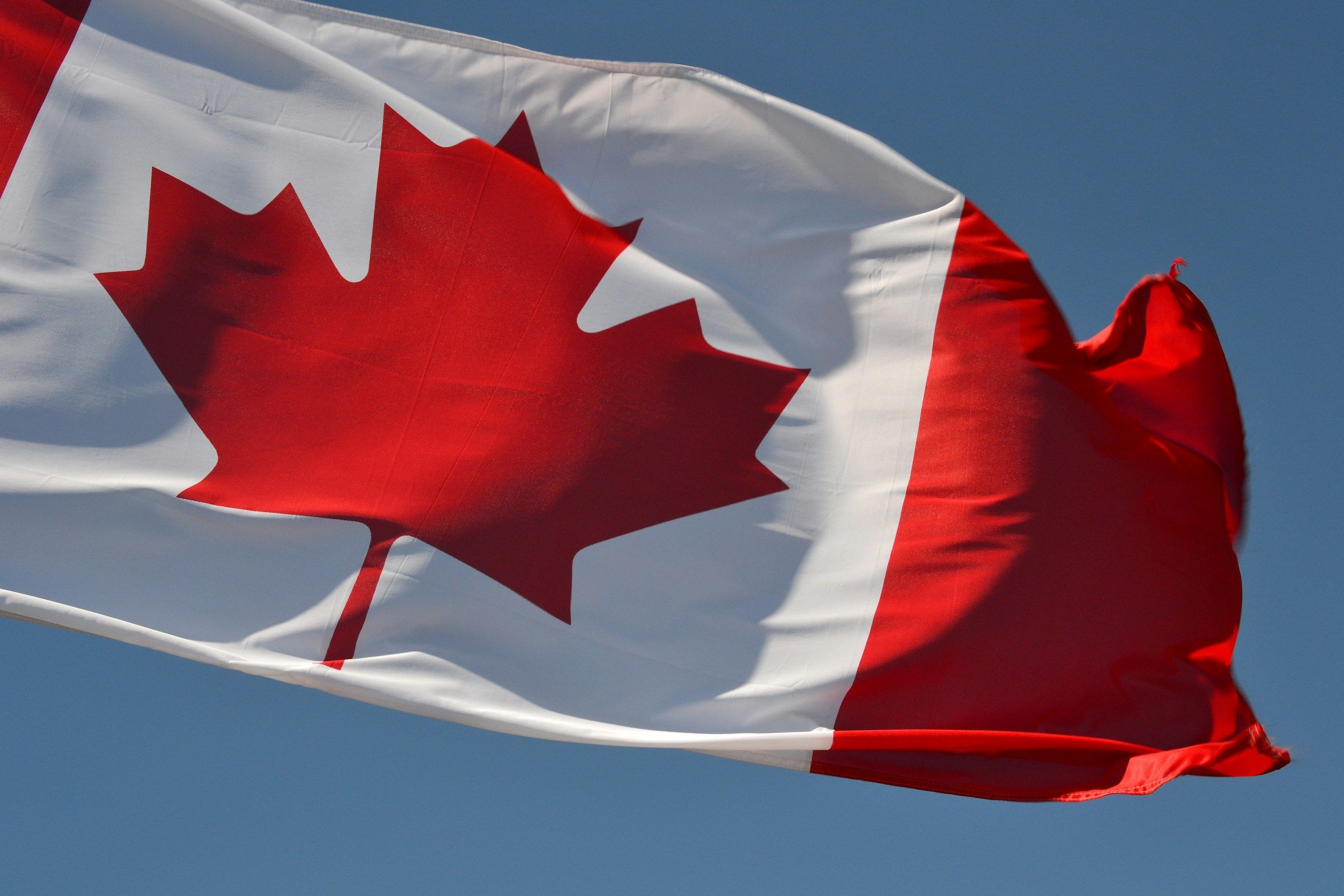 Canadian flag waving on a cruise ship under a blue sky in Ontario