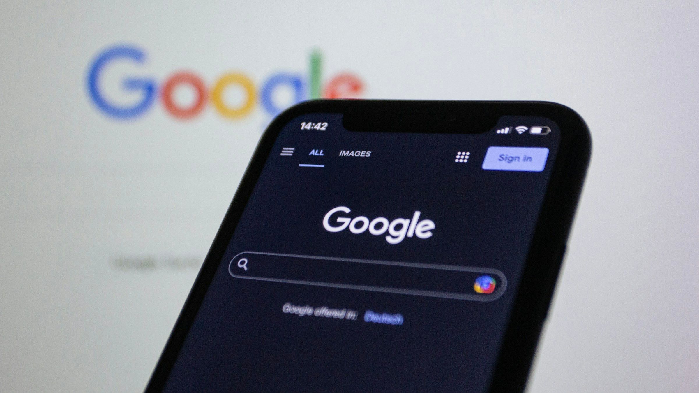 A close-up of a smartphone with the Google logo in the background