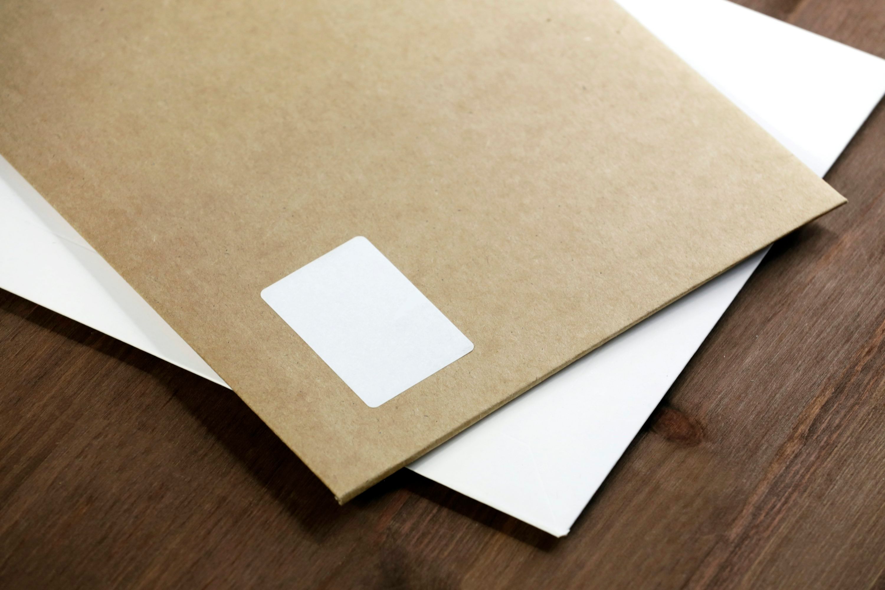 White moving paperwork on a brown wooden table beside a pen.