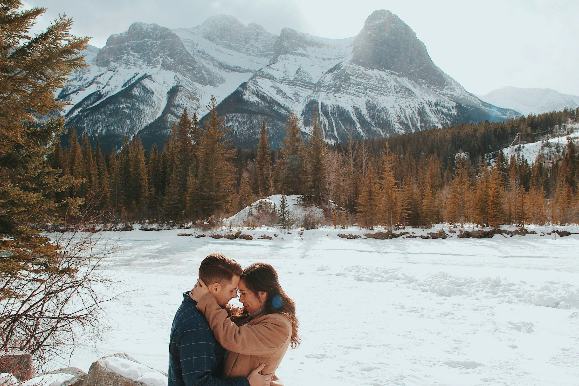 A couple embracing outdoors with mountains behind them