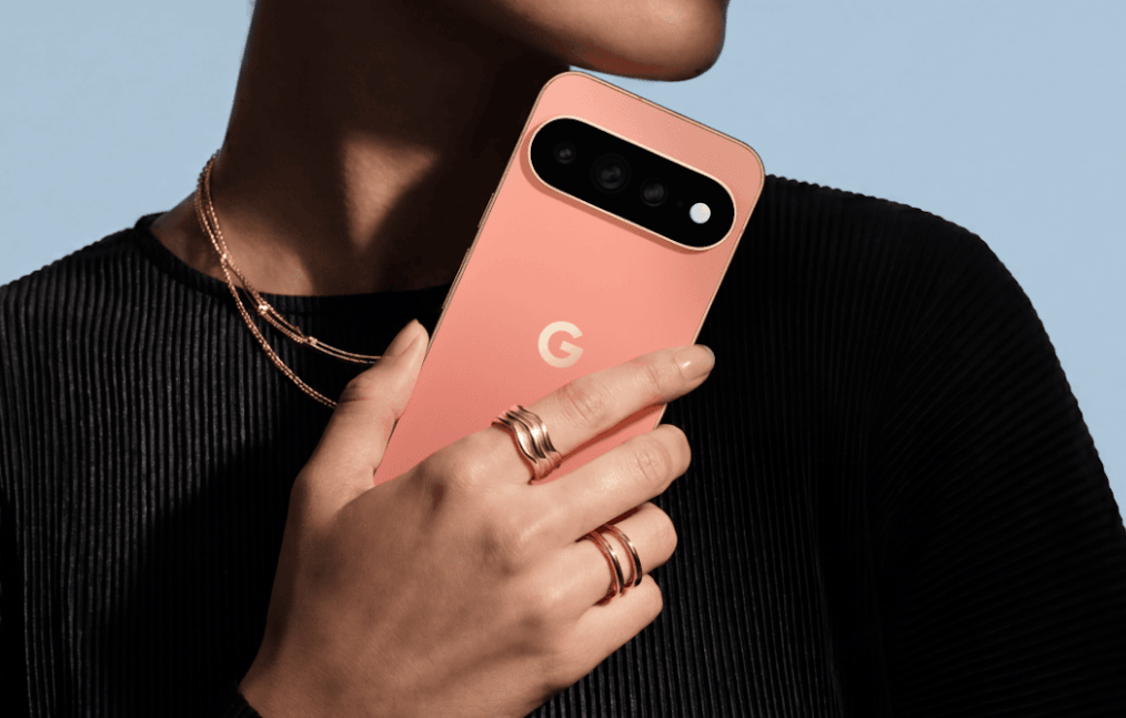 Person holding a coral Google Pixel phone against a pale blue background.