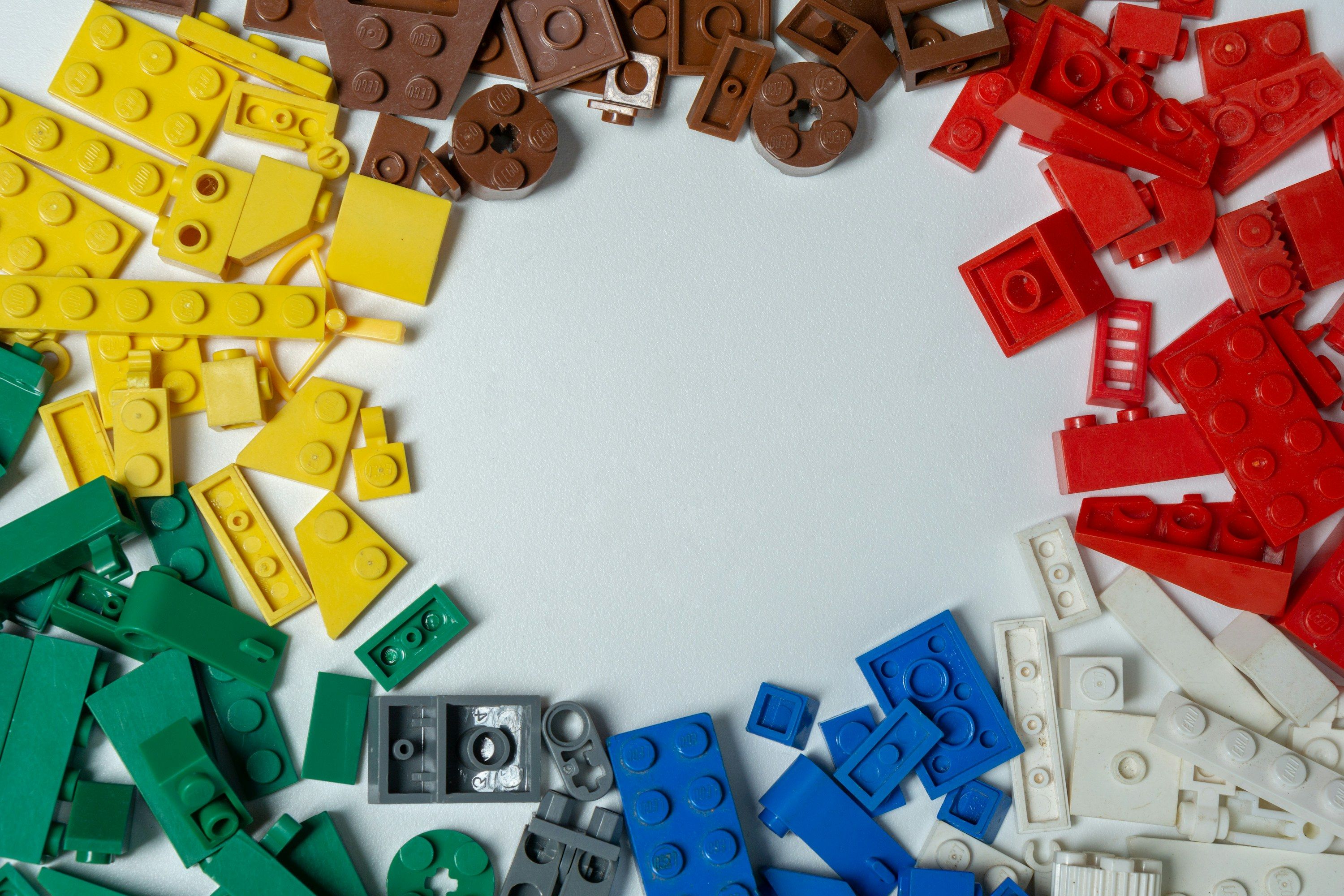 Blue, red, yellow and green LEGO blocks on a white background.