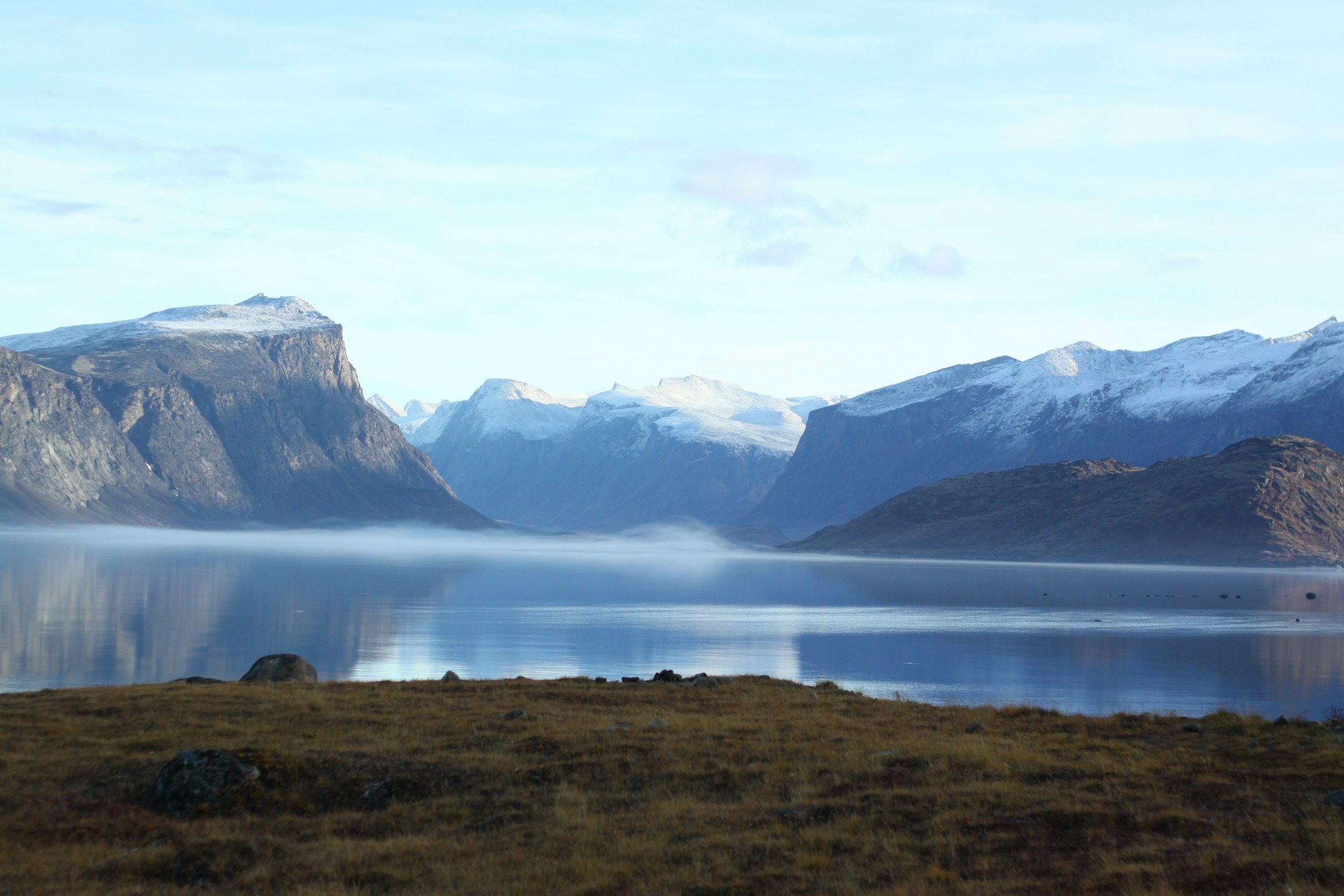 Tundra and still water below steep bare mountains in the Arctic
