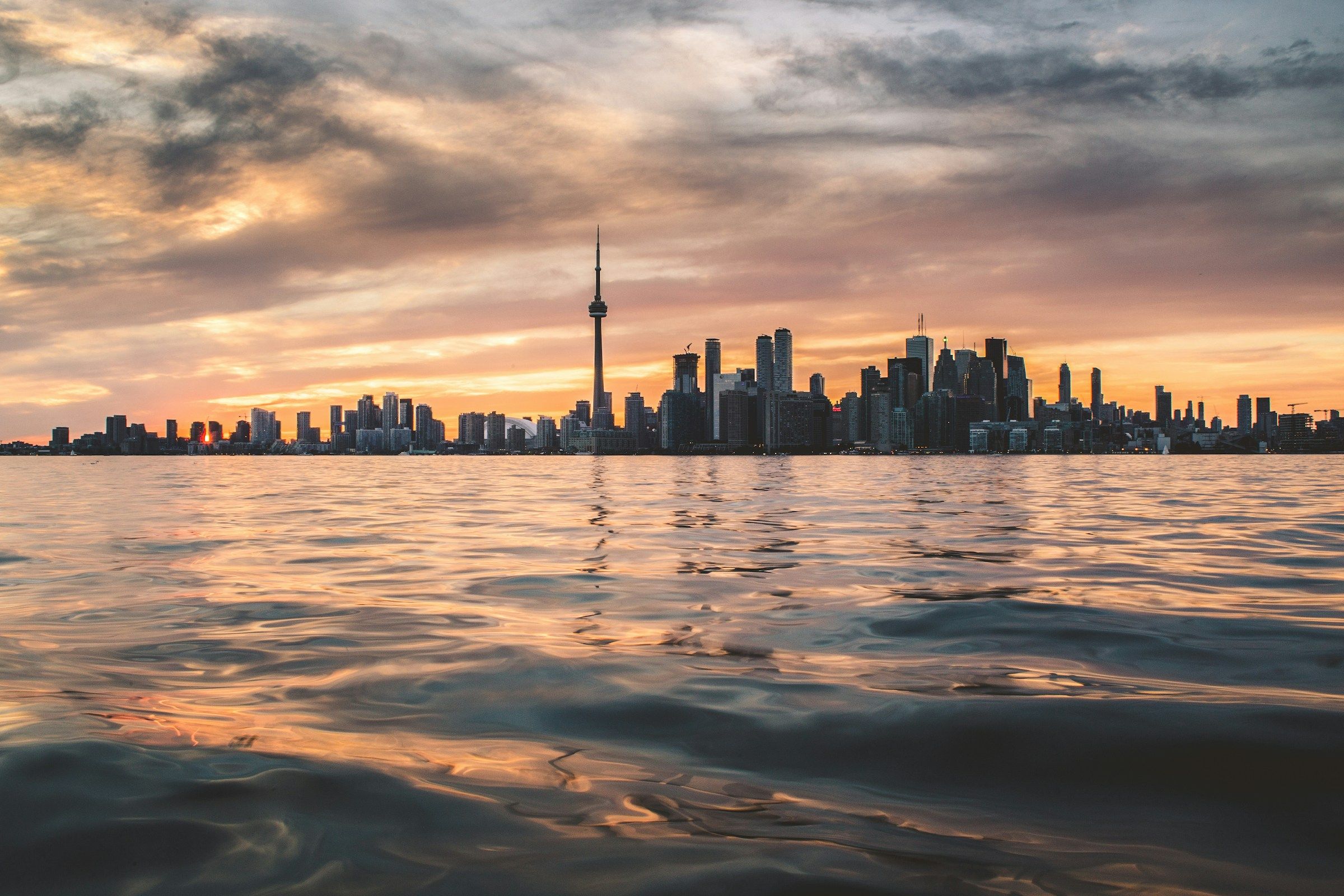 Toronto skyline and CN Tower across Lake Ontario beneath a cloudy sky