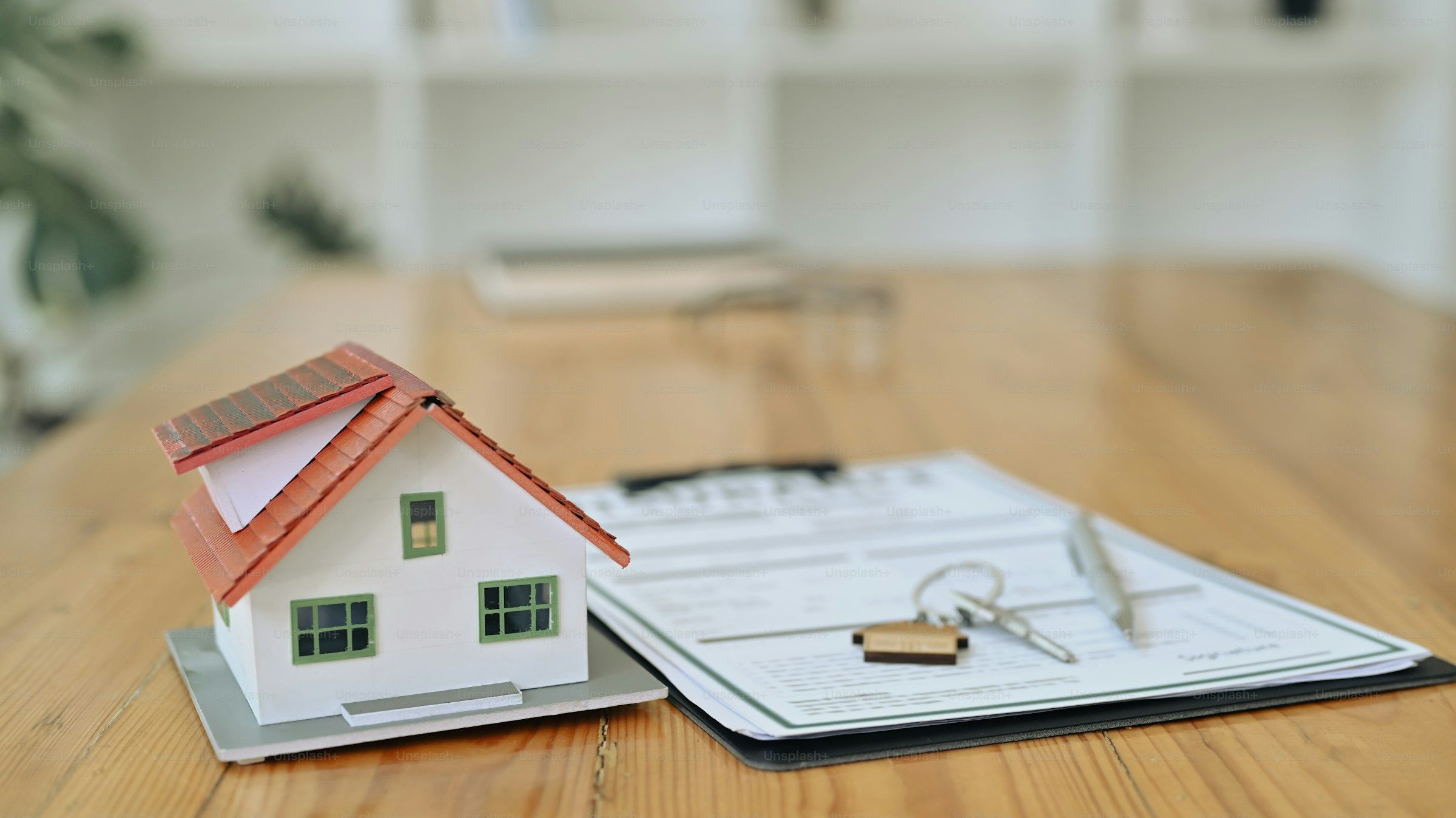 A house model, keys and contract document on a wooden table