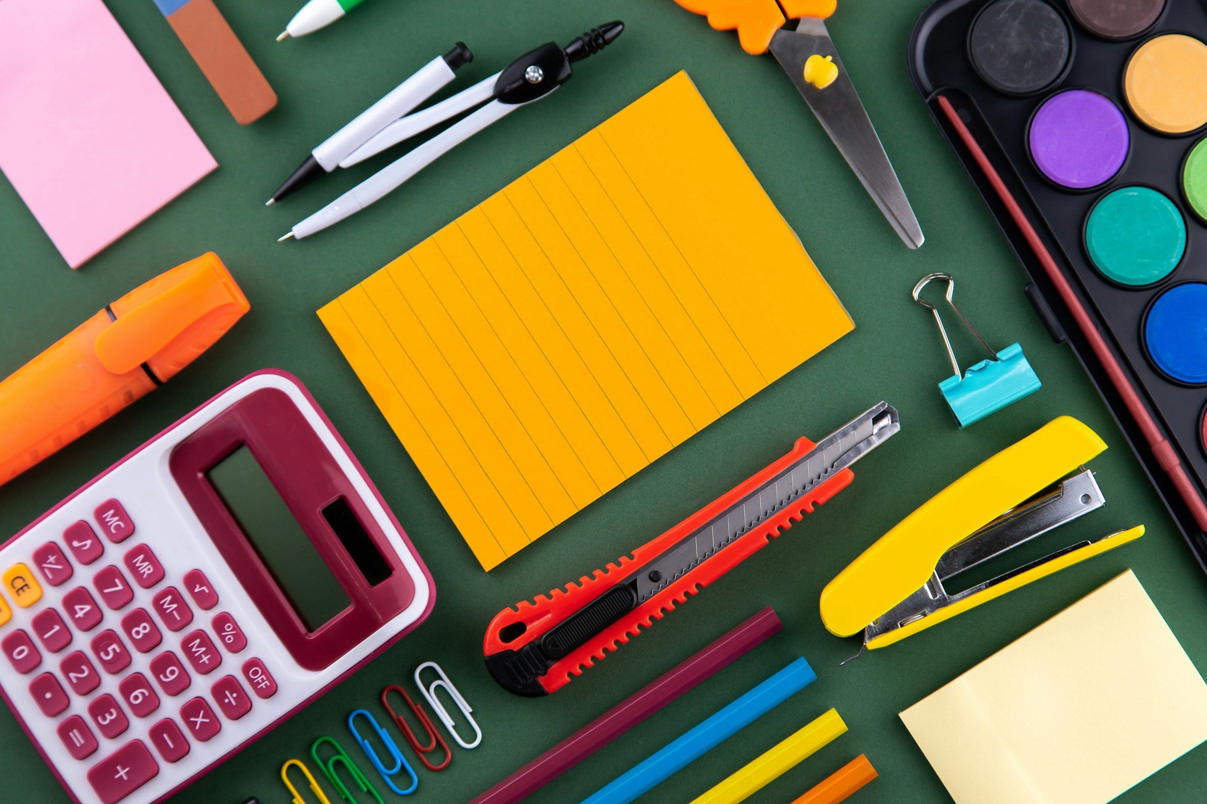 Colourful school and office supplies arranged on a purple desk with space for writing