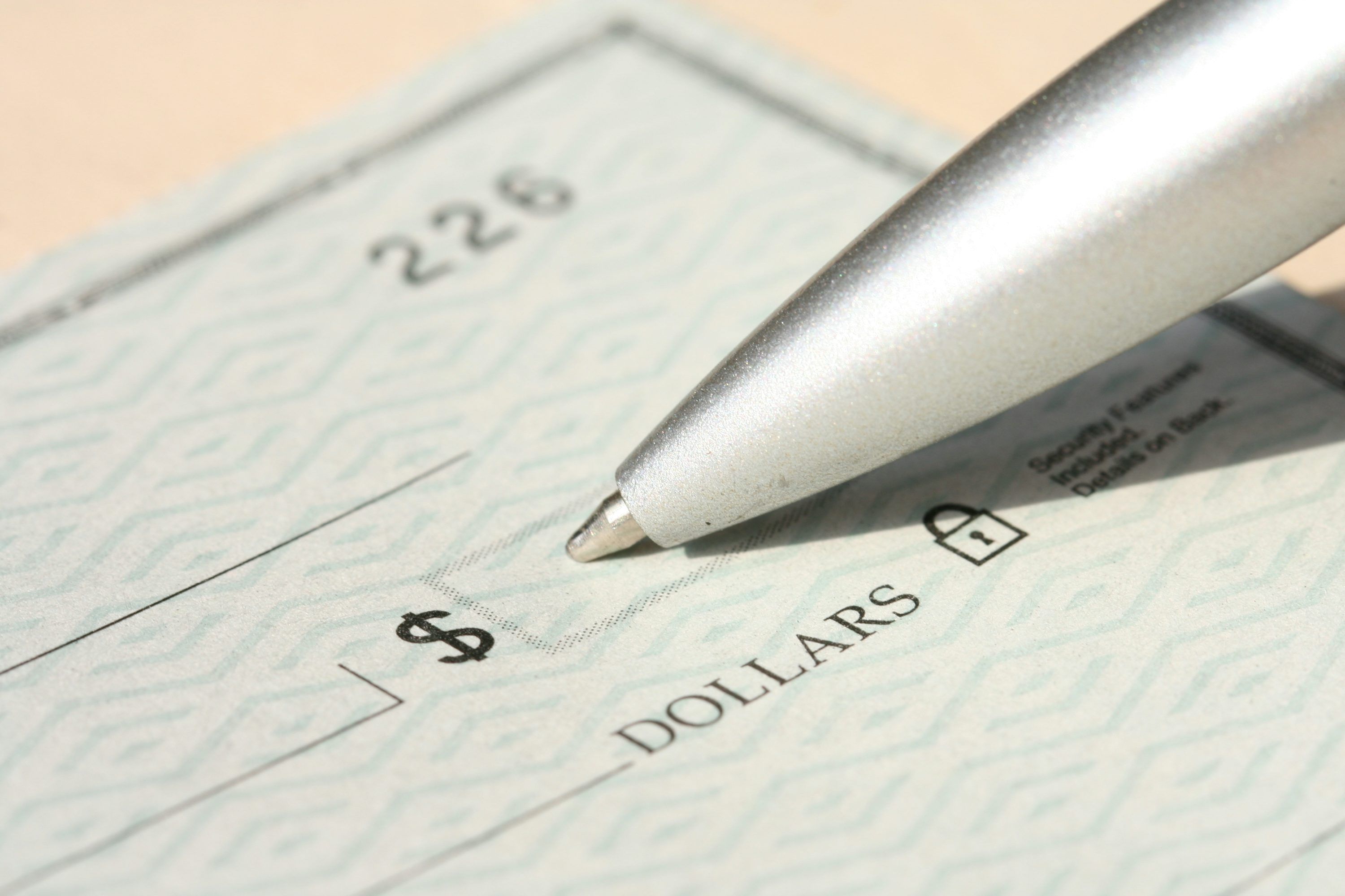 Pen poised over a cheque on a desk for a Canadian direct deposit guide.