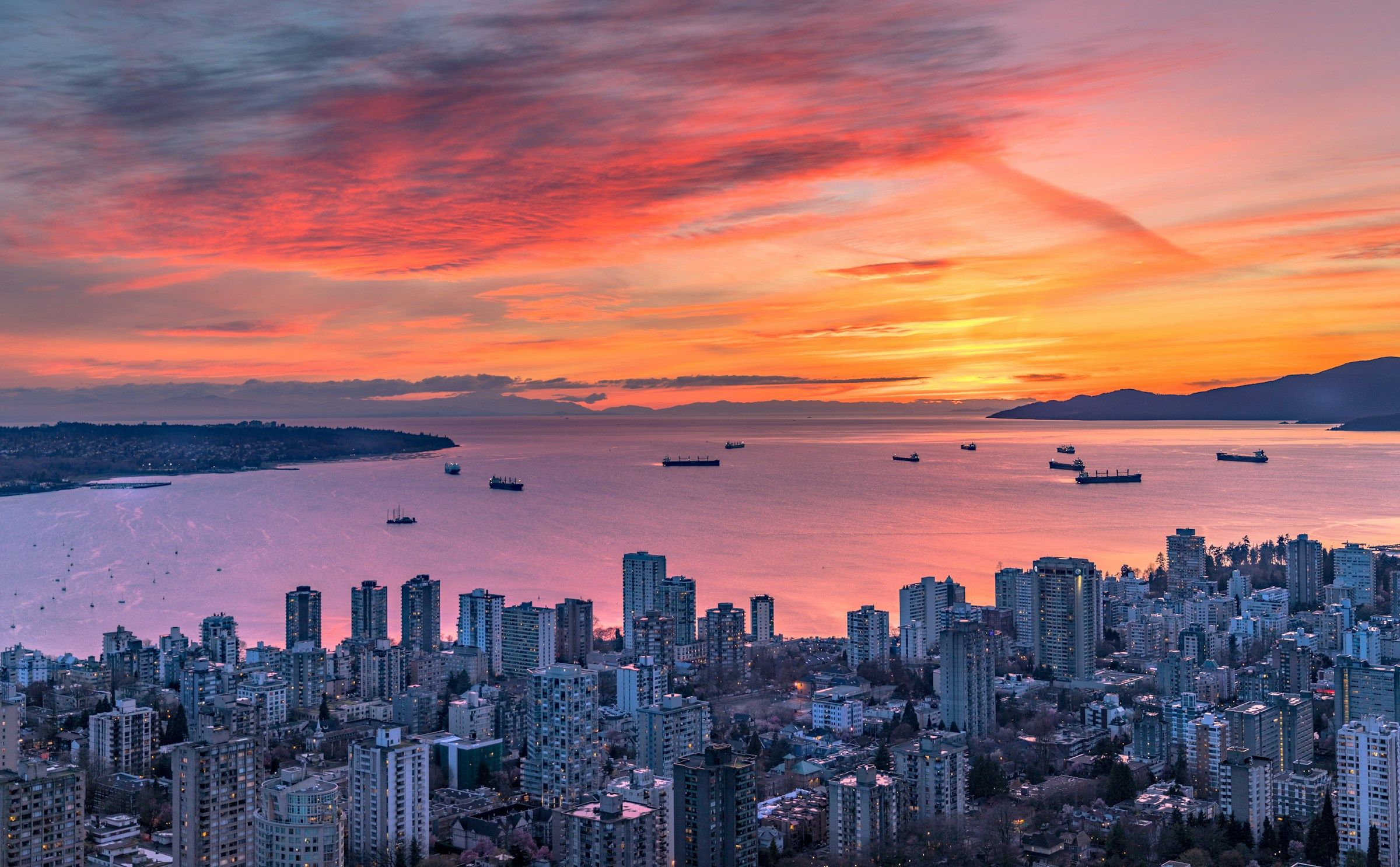 Aerial view of Vancouver and English Bay under a vivid pink and orange sunset