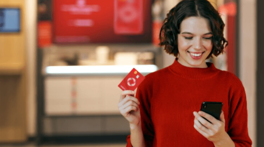 A woman holding a red Rogers credit card while looking at her phone