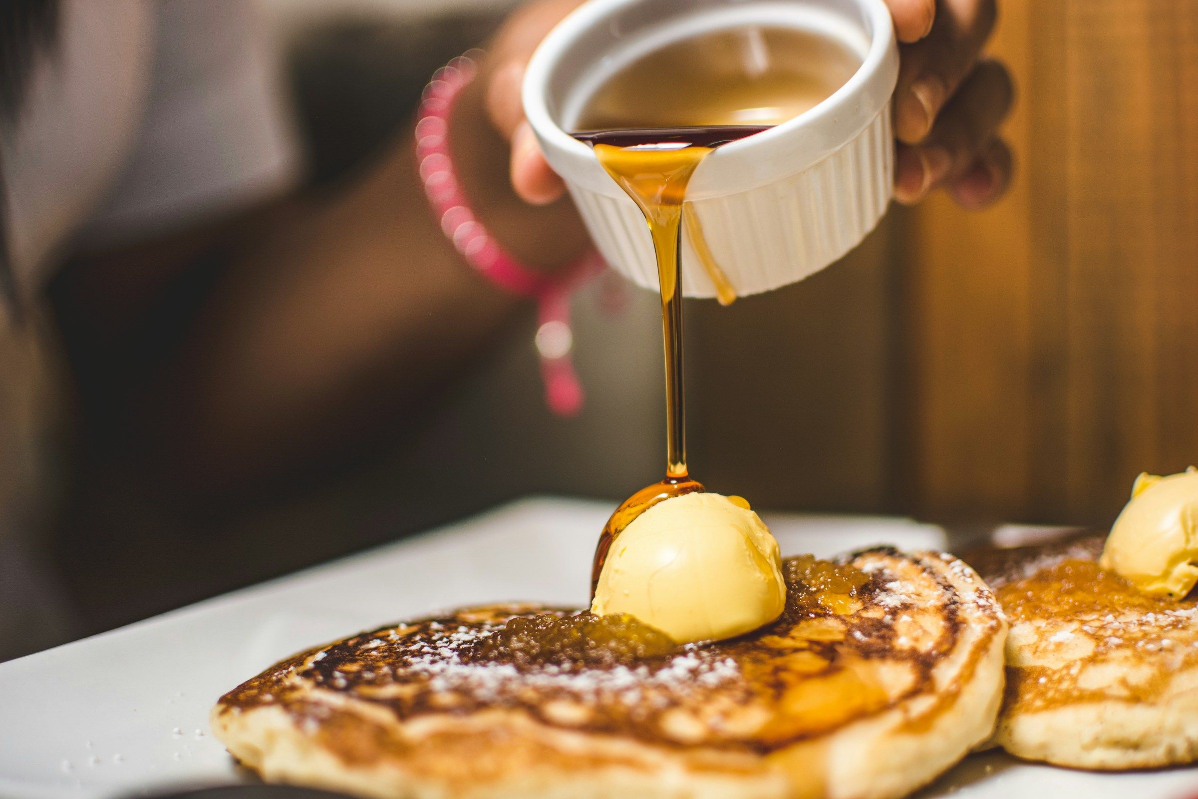 Person pouring syrup over pancakes