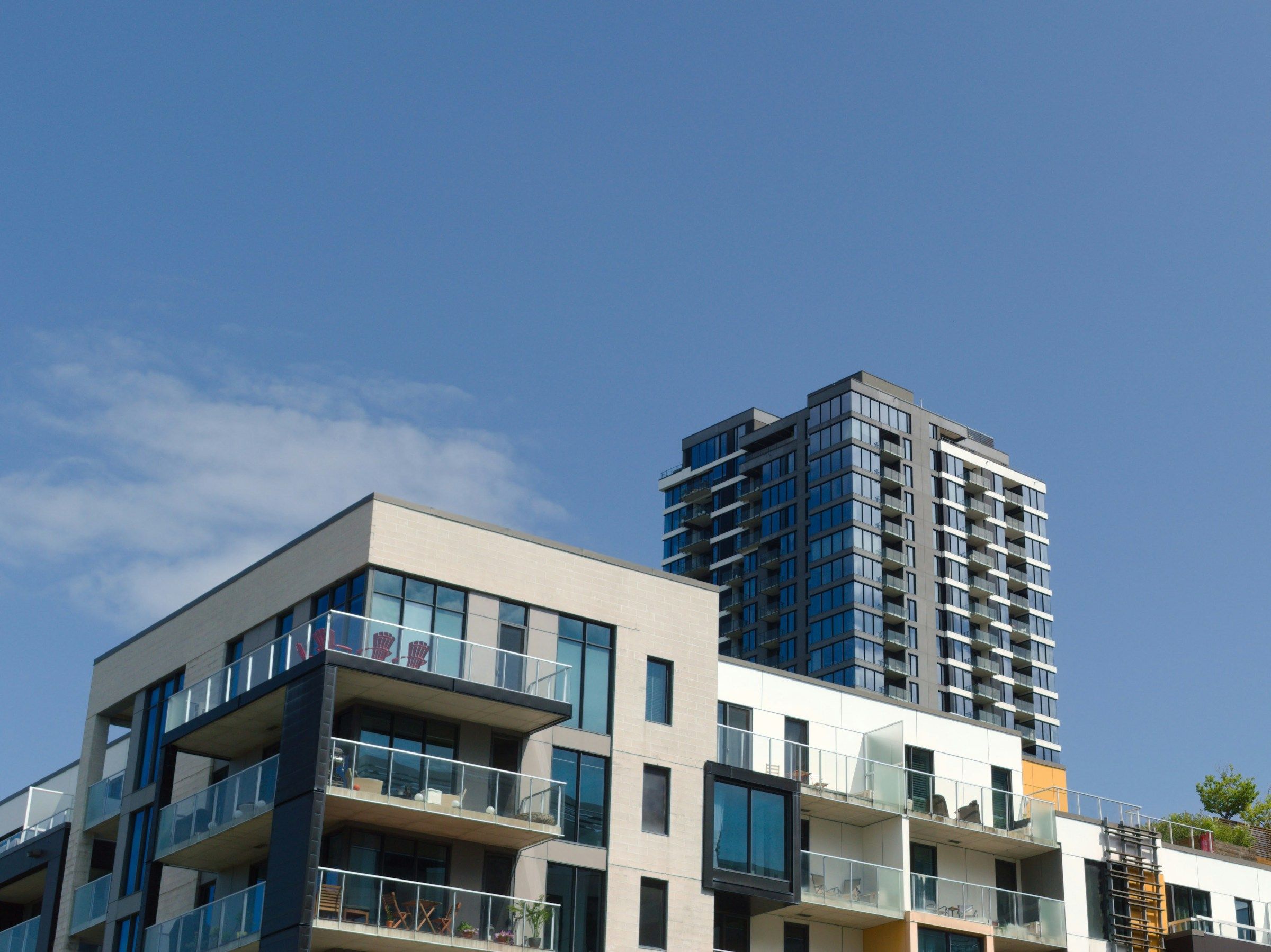 Two residential high-rise buildings seen from below against a blue sky